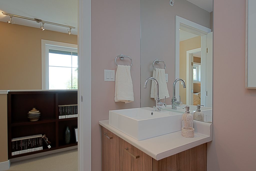 A modern bathroom vanity with a square white basin, chrome taps and a large mirror